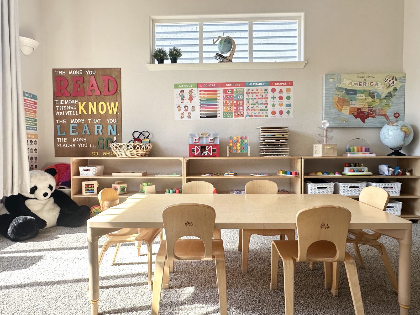Our classroom with wooden tables, chairs and learning shelves